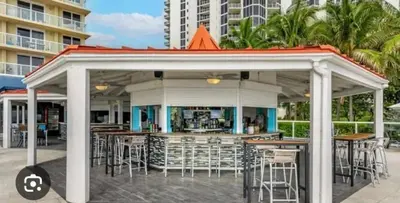 a gazebo with tables and chairs in front of a building at City view with balcony on the Beach in Sunny Isles Beach