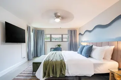 a bedroom with a large bed and a flat screen tv at Central 3BD wPool and Covered Patio 10 min to FLL in Fort Lauderdale