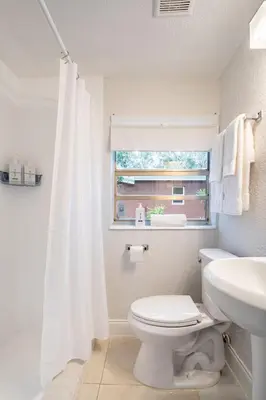 a bathroom with a toilet and a sink and a window at Central 3BD wPool and Covered Patio 10 min to FLL in Fort Lauderdale