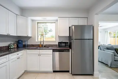 a kitchen with white cabinets and a stainless steel refrigerator at Central 3BD wPool and Covered Patio 10 min to FLL in Fort Lauderdale