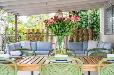 a table with a vase of flowers on a patio at Central 3BD wPool and Covered Patio 10 min to FLL in Fort Lauderdale
