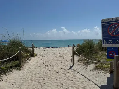 a sandy beach with a sign next to the ocean at Castle beach studio,tennis court and swimming pool with beach access in Miami Beach