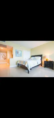 a large bedroom with a bed and a night stand at Castle beach studio,tennis court and swimming pool with beach access in Miami Beach