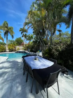 a dining table and chairs on a patio next to a swimming pool at La Dolce Villa in Fort Lauderdale
