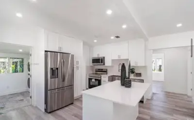 a kitchen with a stainless steel refrigerator and white cabinets at Beautiful House in Coral Gables FL in Miami