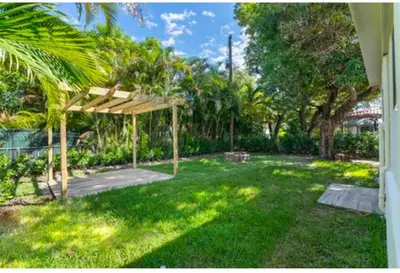 a backyard with a wooden pergola in the grass at Beautiful House in Coral Gables FL in Miami