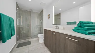 a bathroom with a toilet and a shower with green towels at 2-Bedr Downtown Miami Condo Bay Views in Miami