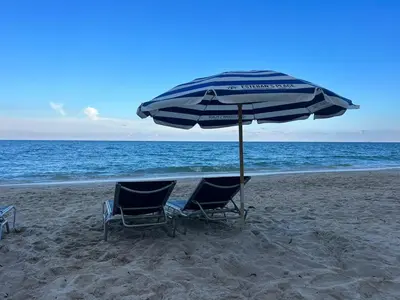 two chairs and an umbrella on the beach at Studio with Service Beach and Pool Hallandale Beach in Hallandale Beach