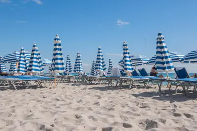 a group of chairs and umbrellas on a beach at Comfy Apt 2 Queen Beds with Pool & Beach in Hallandale Beach