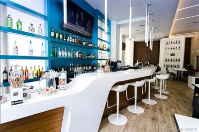 a bar with a white counter and bar stools at Comfy Apt 2 Queen Beds with Pool & Beach in Hallandale Beach