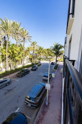 a street with cars parked on the side of a street with palm trees at Amazing 1 Bedroom with Rooftop Pool D309 in Miami Beach