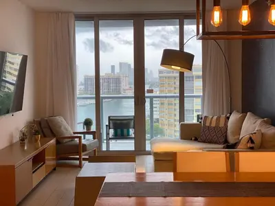 a living room with a couch and a large window at Miami Apt with Amazing Views & Kitchen in Hallandale Beach
