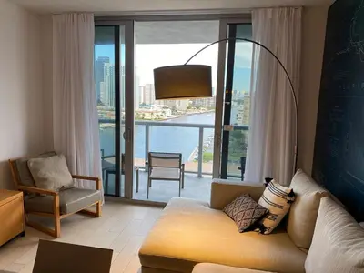 a living room with a couch and a large window at Miami Apt with Amazing Views & Kitchen in Hallandale Beach