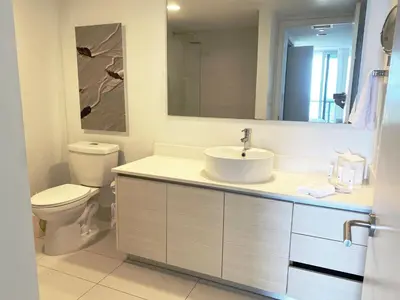a bathroom with a sink and a toilet and a mirror at Miami Apt with Amazing Views & Kitchen in Hallandale Beach