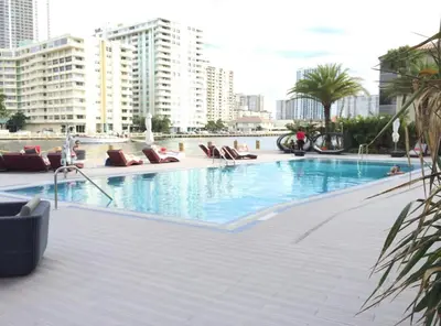 a large swimming pool with lounge chairs and buildings at Miami Apt with Amazing Views & Kitchen in Hallandale Beach