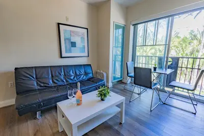 a living room with a black leather couch and a table at Beautiful 1 Bedroom with Rooftop Pool D203 in Miami Beach