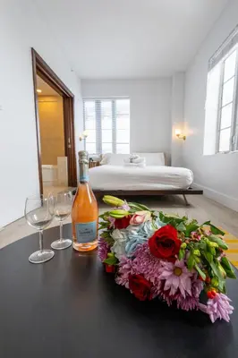 a bottle of wine and flowers on a table in a room at Beautiful Studio with Rooftop pool B309 in Miami Beach