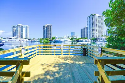 a dock with benches and a river with tall buildings at Modern Luxury Condo Near Beach & Aventura Mall in Aventura