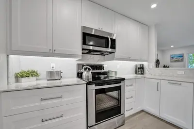 a white kitchen with a stove and a microwave at Private Room in Spacious 3-Bedroom Home in Fort Lauderdale