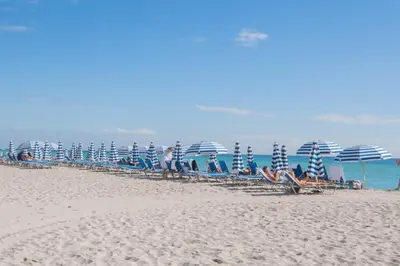 a group of chairs and umbrellas on a beach at Studio Apmt 2 Beds with pool and gym in Hallandale Beach