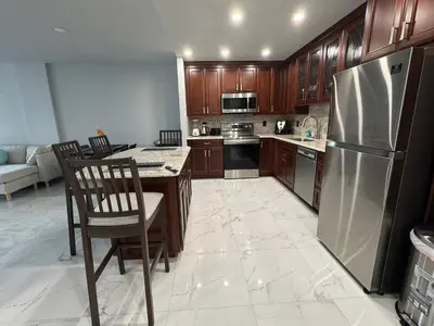 a kitchen with wooden cabinets and a stainless steel refrigerator at Modern Apartments Ocean Reserve Sunny Isles Beach in Sunny Isles Beach