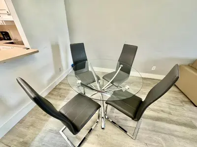 a glass table and four black chairs in a room at Ocean Reserve Luxury Condo Sunny Isles Beach in Sunny Isles Beach