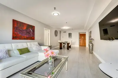 a living room with a white couch and a glass table at Sunny isles Escape-1BR Condo Steps from the Beach! in Sunny Isles Beach