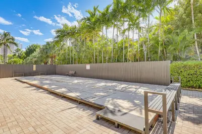 a patio with a fence and a bench and trees at Sunny isles Escape-1BR Condo Steps from the Beach! in Sunny Isles Beach