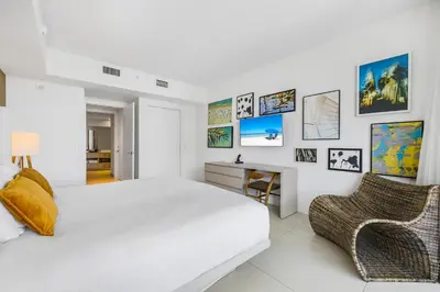 a white bedroom with a bed and a desk and chairs at Beachfront Bliss W Ocean Views in Hollywood