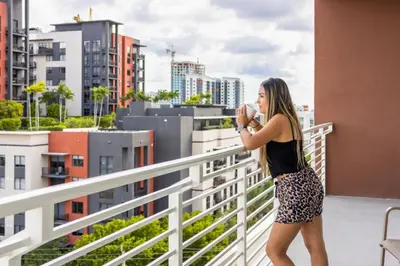 a woman standing on a balcony taking a picture of a city at Chic Ft Lauderdale 2BR | Pool + Nightlife in Fort Lauderdale