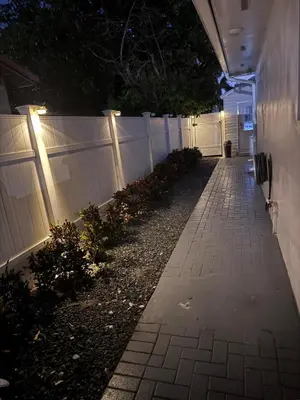 a fence with lights on the side of a sidewalk at Hallandale Beach Club in Hallandale Beach