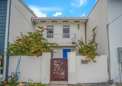 a white house with a gate and a balcony at Vista Mar Scenic 3BR Family Waterfront w Private Dock in North Miami