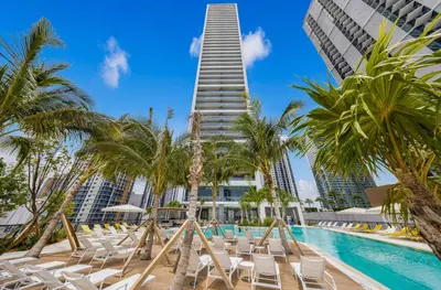 a pool with chairs and a tall building at 2-BD Downtown Miami Condo with City Views in Miami