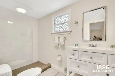 a bathroom with a toilet and a sink and a mirror at 3 Home 12 bedroom compound with Pool and BBQ sleeps 24 in Miami