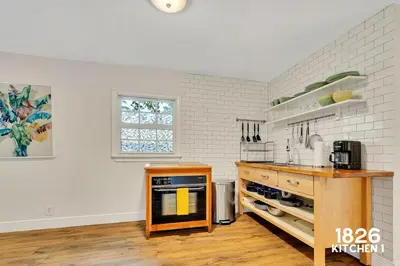 a kitchen with white brick walls and a wooden counter at 3 Home 12 bedroom compound with Pool and BBQ sleeps 24 in Miami