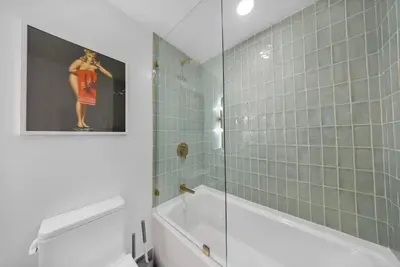 a bathroom with a tub and a shower with a picture of a woman at 1-BD Condo in DTW Miami - City Views in Miami