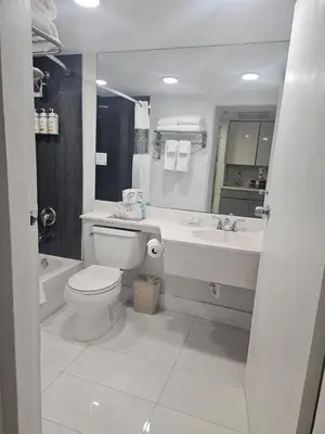a white bathroom with a toilet and a sink at Ocean front paradise studio with ocean view and beach exit in Sunny Isles Beach