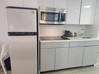 a white kitchen with a refrigerator and a microwave at Ocean front paradise studio with ocean view and beach exit in Sunny Isles Beach