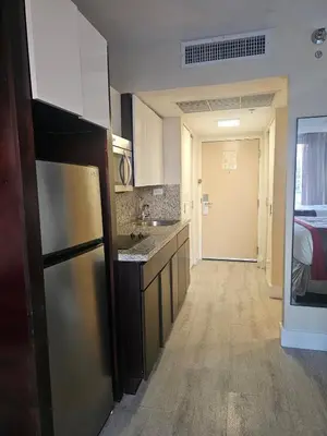 a kitchen with a refrigerator and a room with a bed at Beach Studio with City View in Sunny Isles Beach