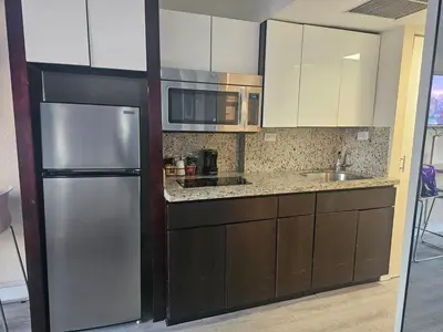 a kitchen with brown cabinets and a stainless steel refrigerator at Beach Studio with City View in Sunny Isles Beach