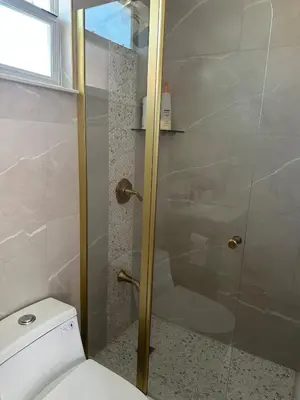 a bathroom with a glass shower door next to a toilet at 2 Nice and Cozy guest house in Opa-locka