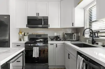 a kitchen with white cabinets and a black stove top oven at Wynwood beautiful Art Deco home with 4 Bedroom in Miami