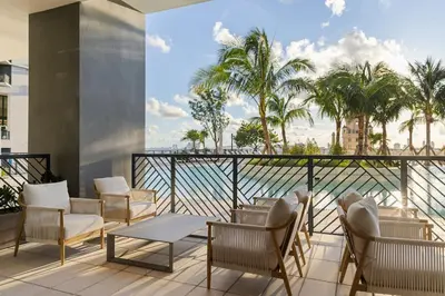 a balcony with chairs and tables and palm trees at 3002 Downtown Miami apt in front of Kaseya Center with Gym and Pool in Miami