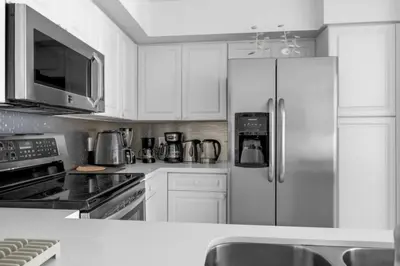 a kitchen with white cabinets and a stainless steel refrigerator at Aventura Mall Apt with Pool a Tennis Court and Free parking in Aventura