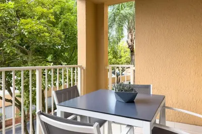 a blue table and chairs on a porch with a window at Aventura Mall Apt with Pool a Tennis Court and Free parking in Aventura