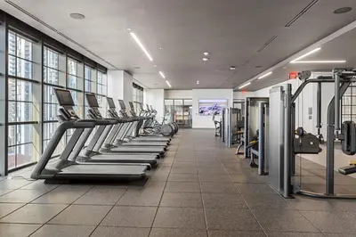 a gym with a row of treadmills and machines at 3312 Modern Apt in front of Kaseya Center with Pool and Gym in Miami
