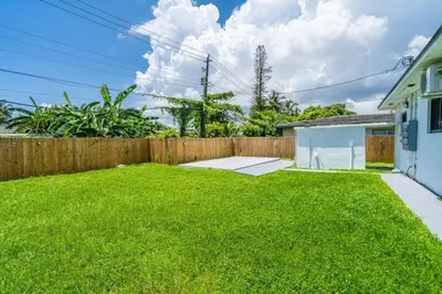 a backyard with a wooden fence and green grass at Unit 2 Cute Studio in North Miami 10min to beach in Miami