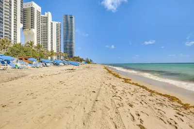 a beach with chairs and umbrellas and the ocean at Sunny Isles Beach Ocean View Studio with Balcony in Sunny Isles Beach