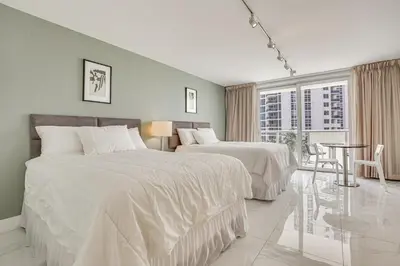 a bedroom with two beds and a table and a window at Sunny Isles Beach Ocean View Studio with Balcony in Sunny Isles Beach
