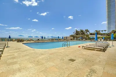 a swimming pool with chairs and a view of the ocean at Sunny Isles Beach Ocean View Studio with Balcony in Sunny Isles Beach